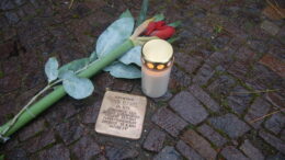 Stolperstein, mit Kerze und Blume.