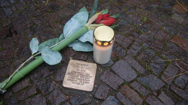 Stolperstein, mit Kerze und Blume.