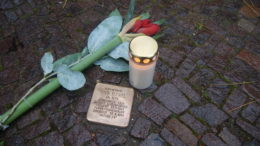 Stolperstein, mit Kerze und Blume.