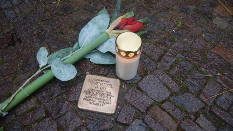 Stolperstein, mit Kerze und Blume.