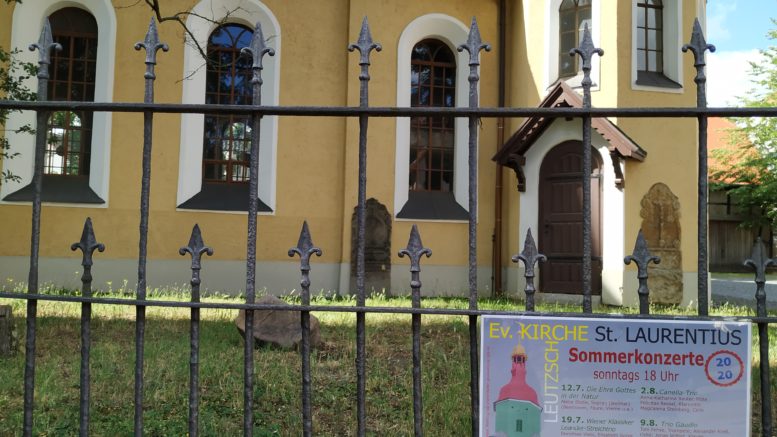 Am Kirchenzaun der Leutzscher Kirche hängt ein Ankündigungsplakat für die Sommerkonzerte.